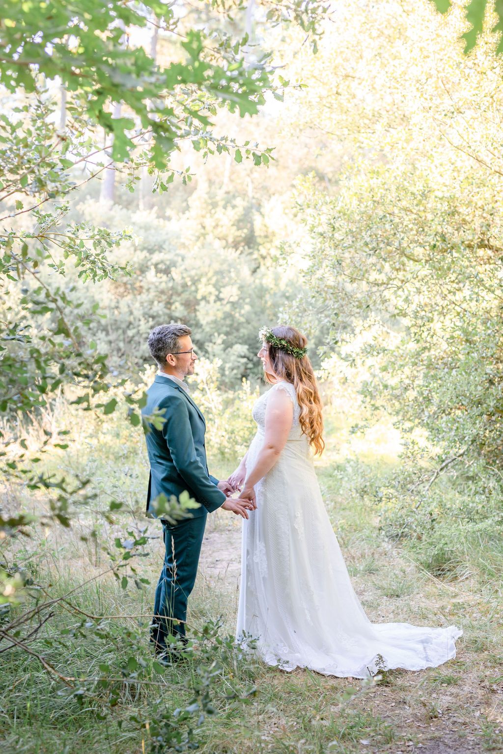 Romantic first look wedding moment captured in a sunlit wooded setting.