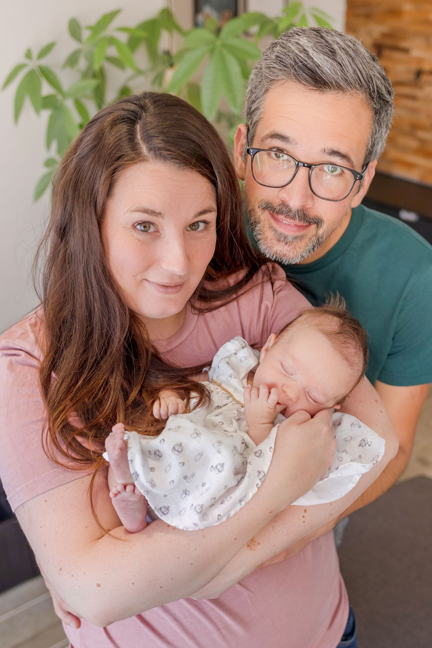 Intimate family portrait showing tender moments with a newborn baby in soft lighting.