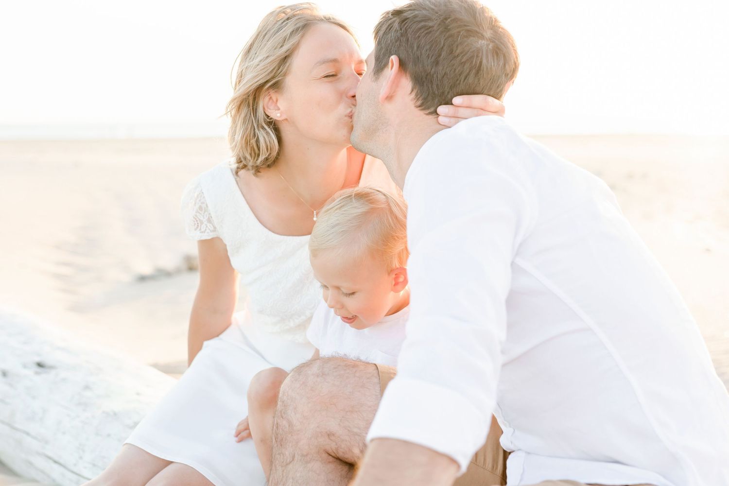 Intimate family moment captured on a sandy beach during golden hour.
