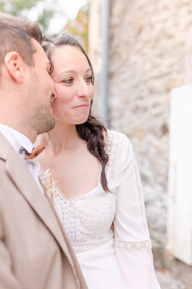 Soft, romantic portrait of couple in vintage wedding attire against stone wall.