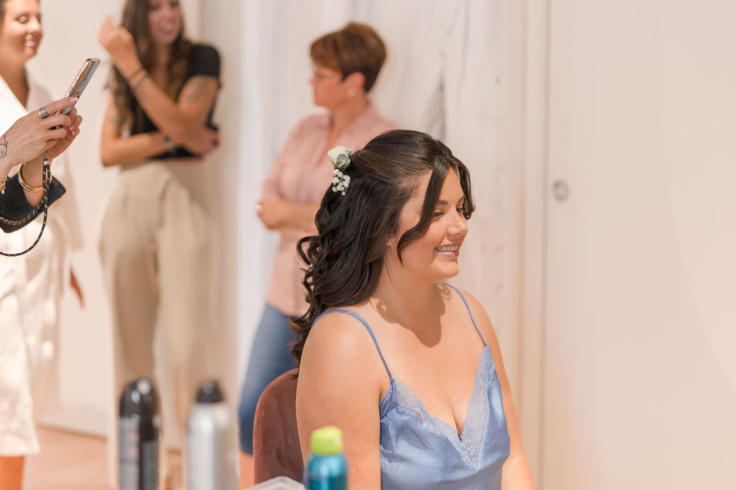 Someone wearing a blue satin dress smiles during a special occasion preparation.