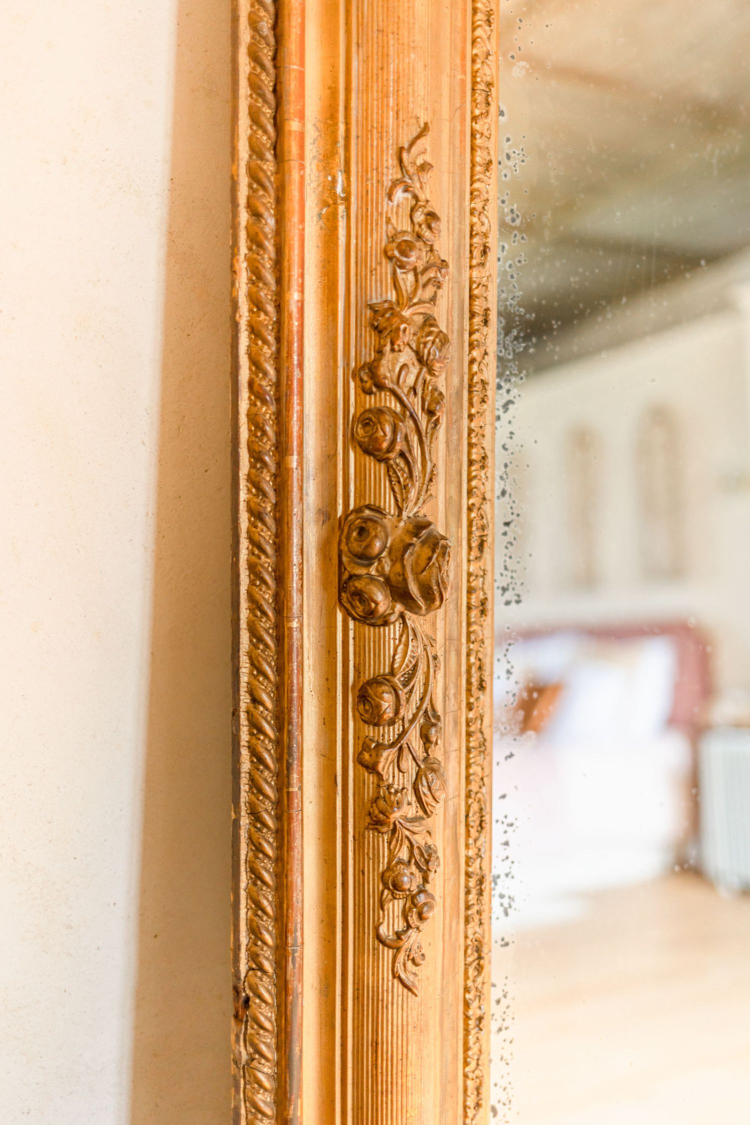 Close-up detail of an ornate gold mirror frame with decorative carvings.