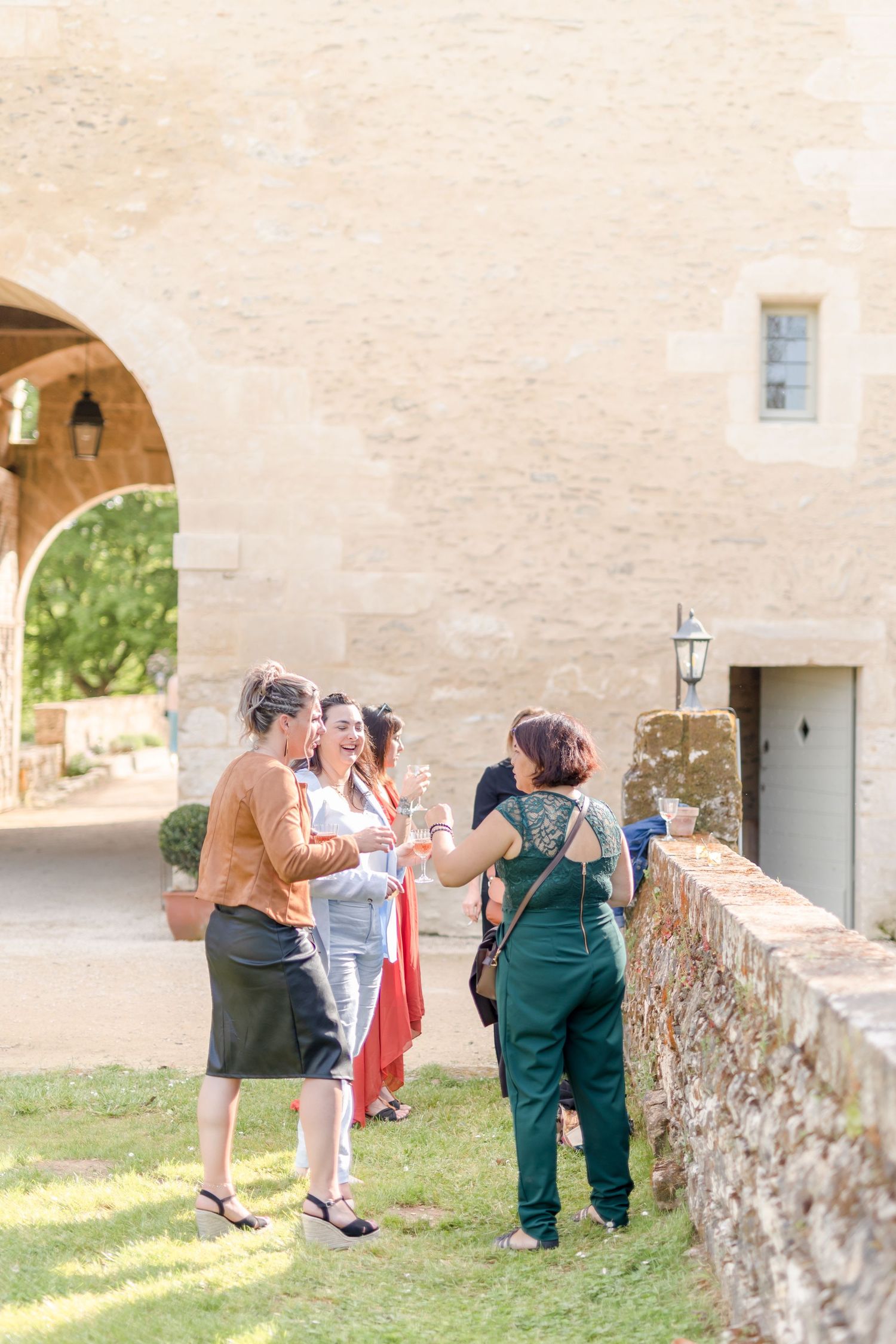 Small group chatting on a stone terrace beside an arched entrance of a historic building.
