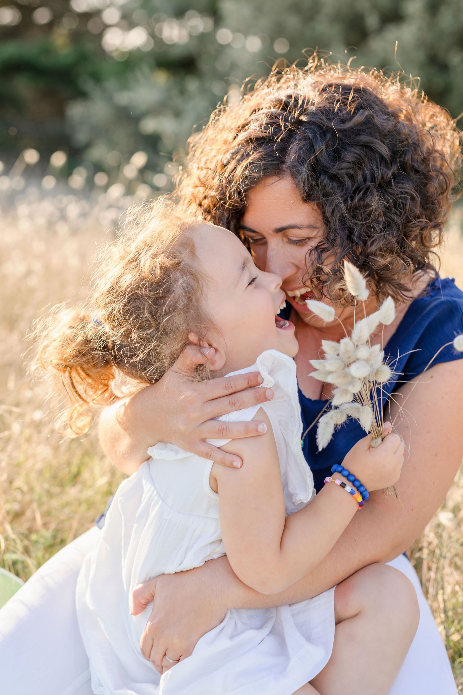 An intimate moment of joy and laughter shared in a sunlit field of tall grass.
