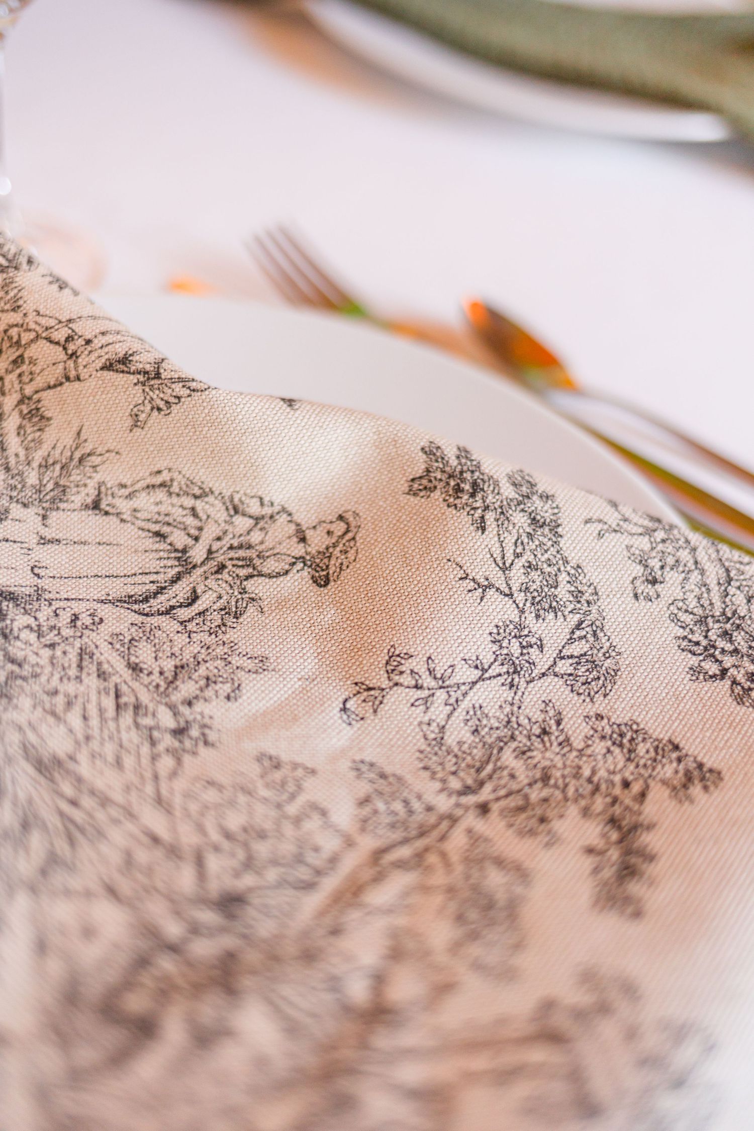 Close-up of delicate toile pattern on light beige fabric.
