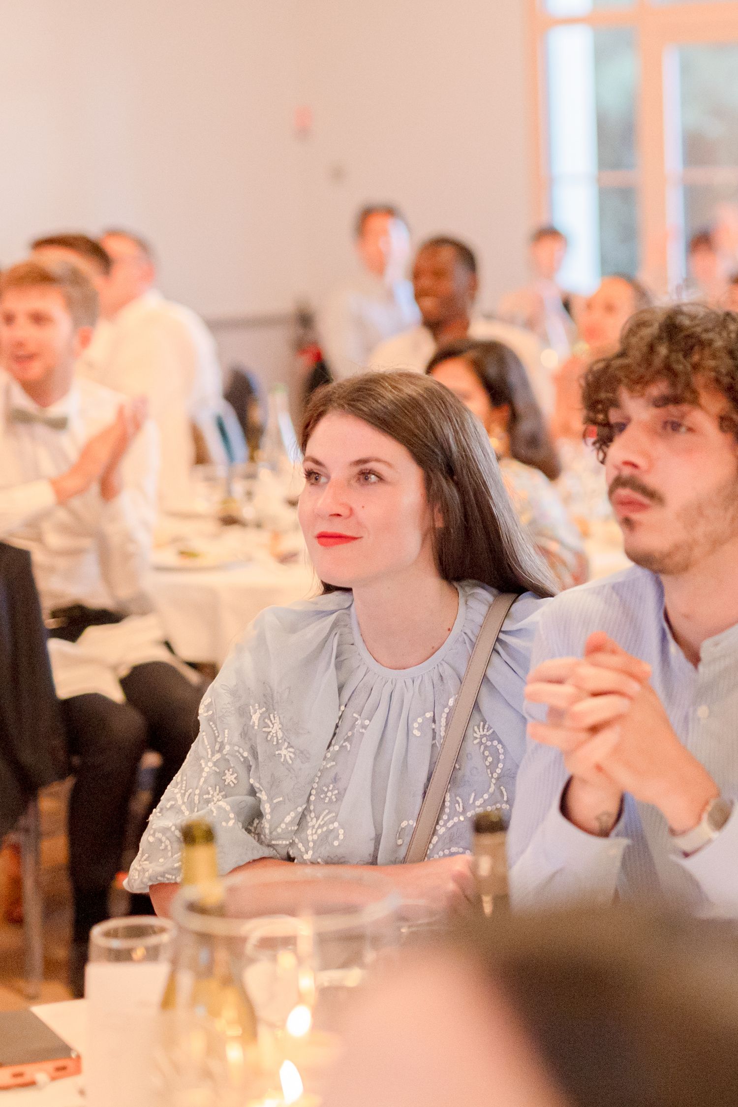 Guests seated at elegantly decorated reception tables in a warmly lit banquet hall.