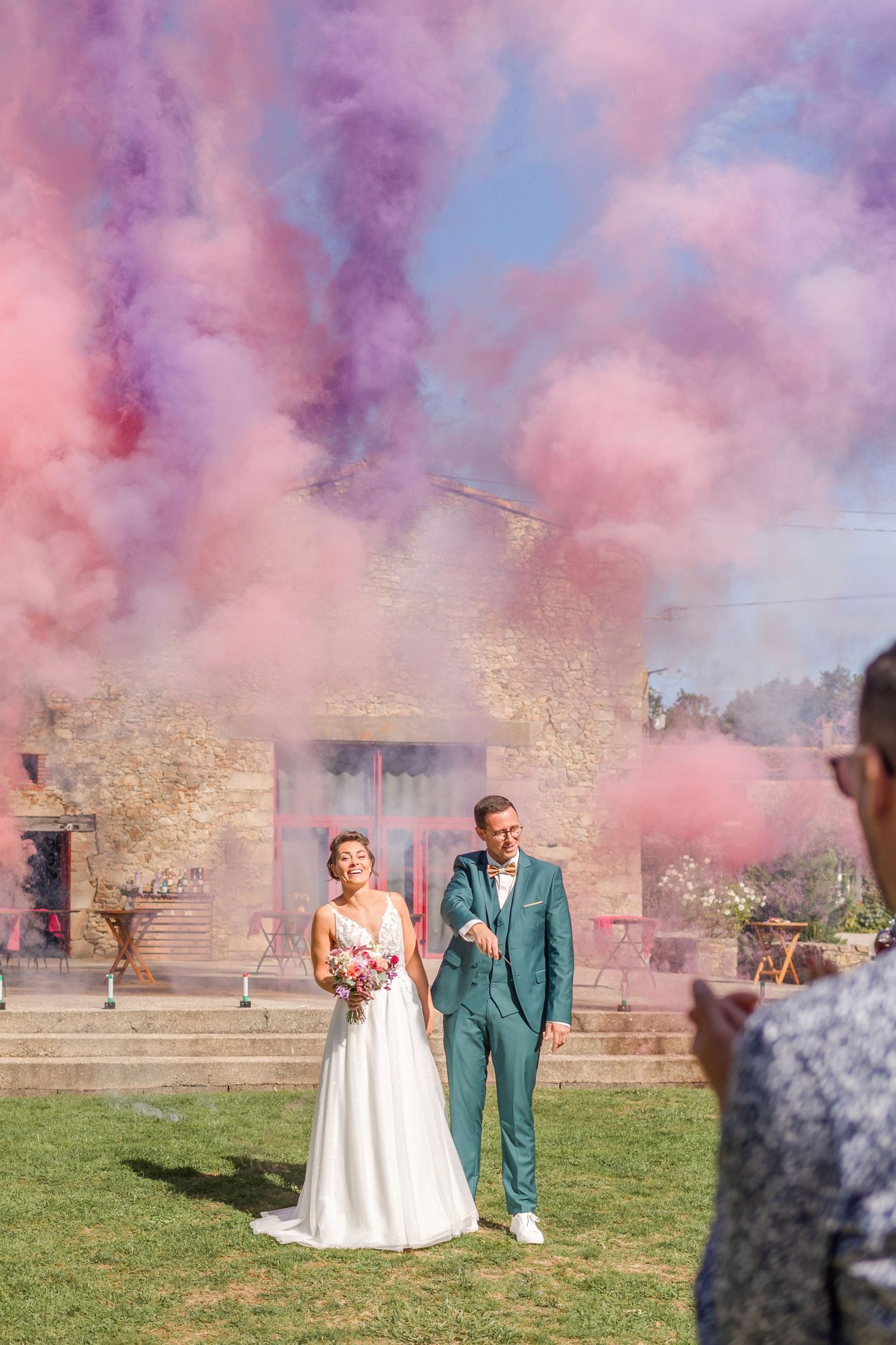 Colorful smoke effects fill the air during an outdoor wedding photoshoot.