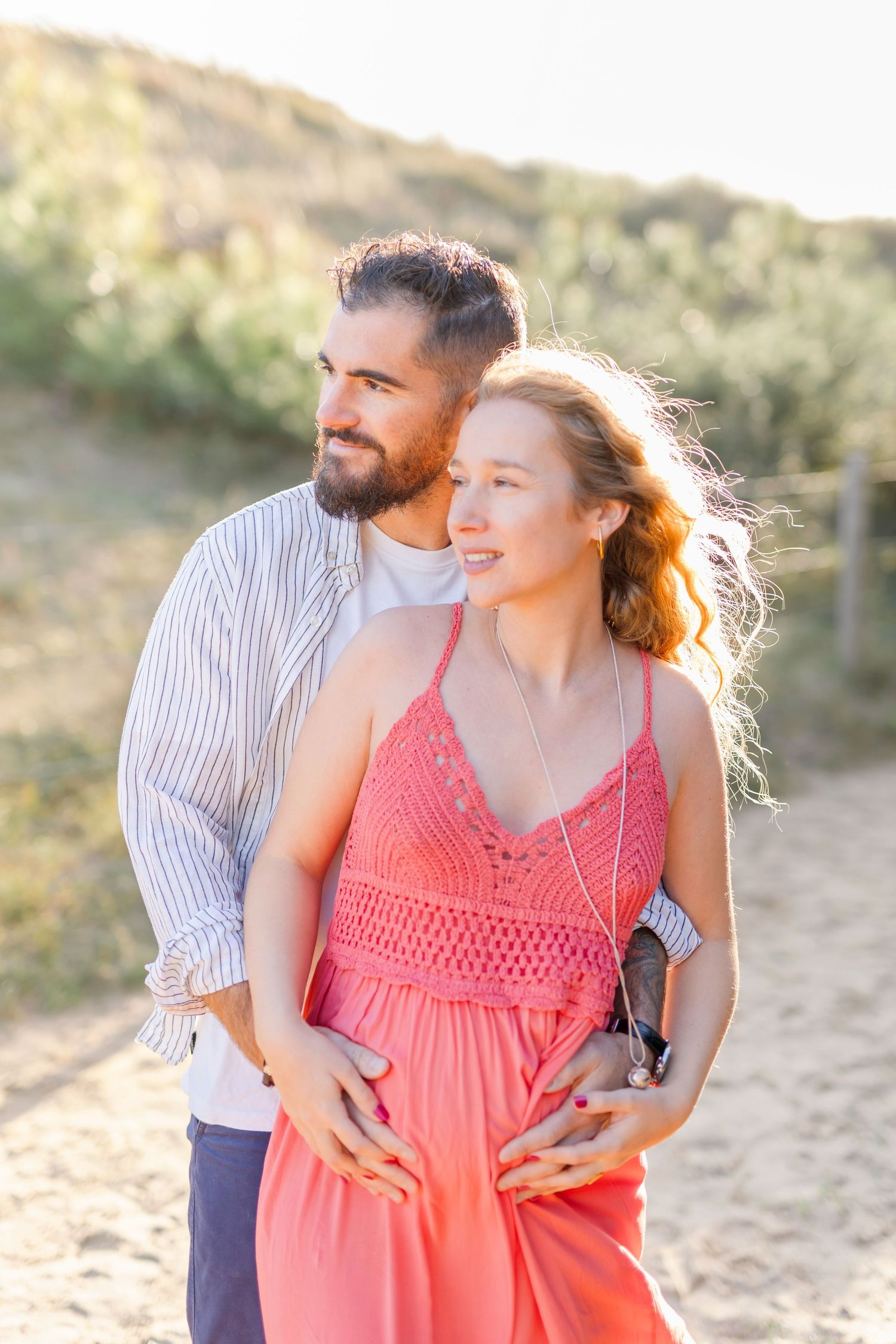 Sun-drenched portrait of couple outdoors with natural backdrop.