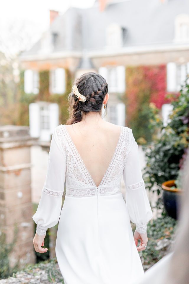 Back view of bride in elegant white dress with lace details and flowing sleeves.