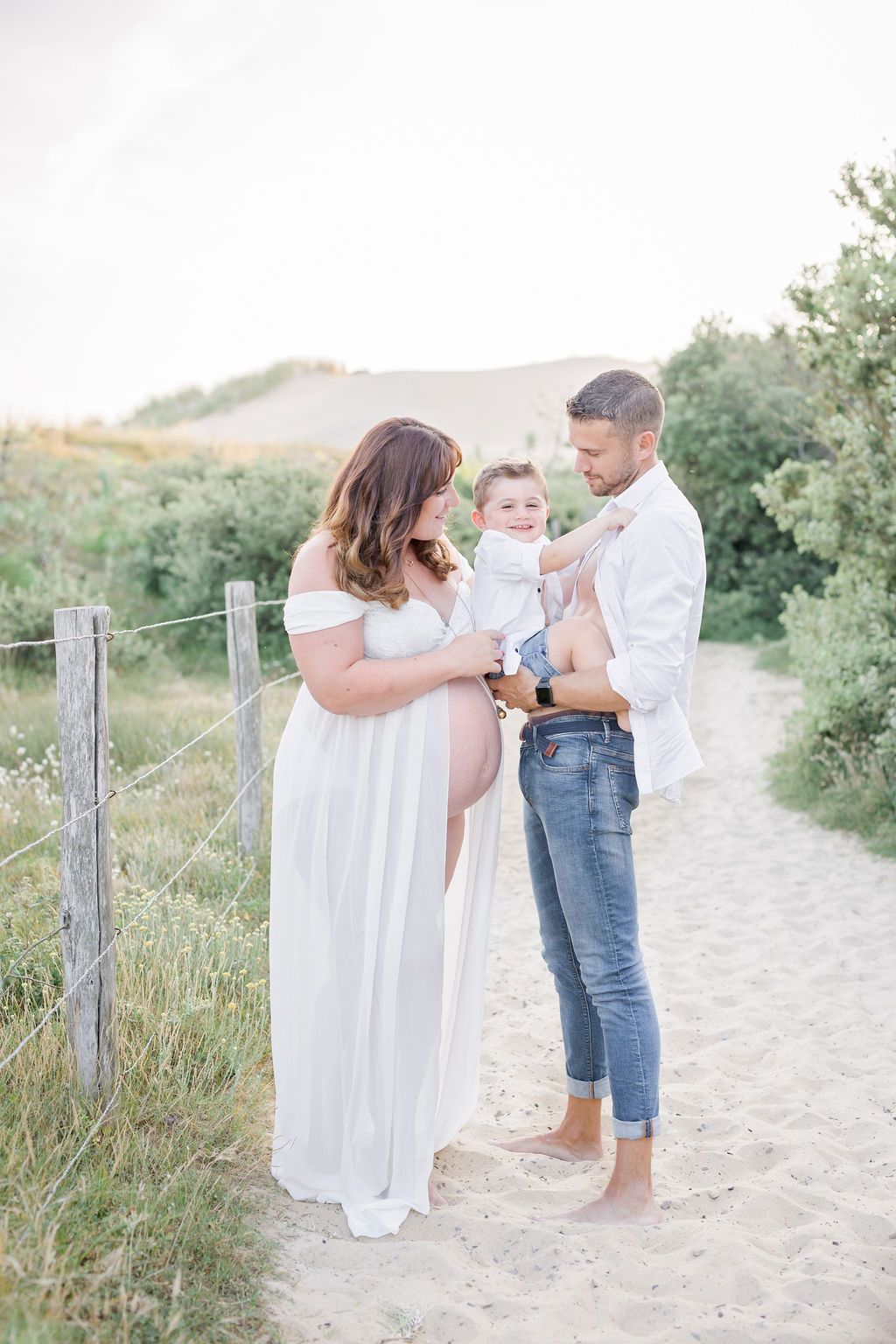 Family sharing tender moments on sandy coastal trail during golden hour photoshoot.