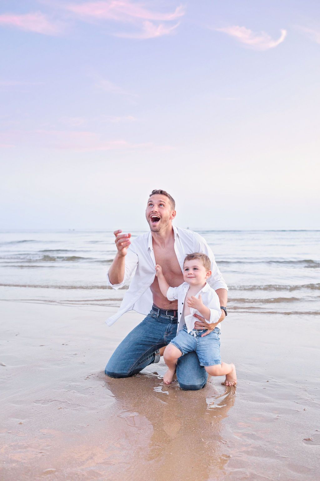 Joyful beach portrait of father and son laughing together at sunset.