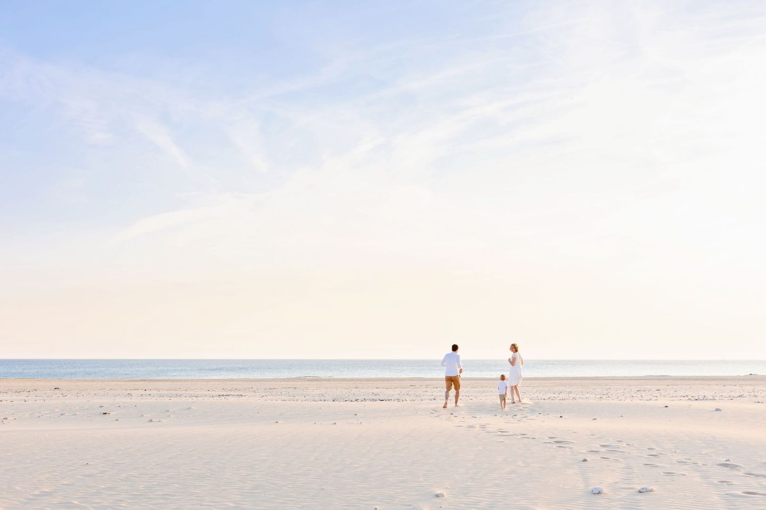 Two distant figures walking on an empty beach during sunset.