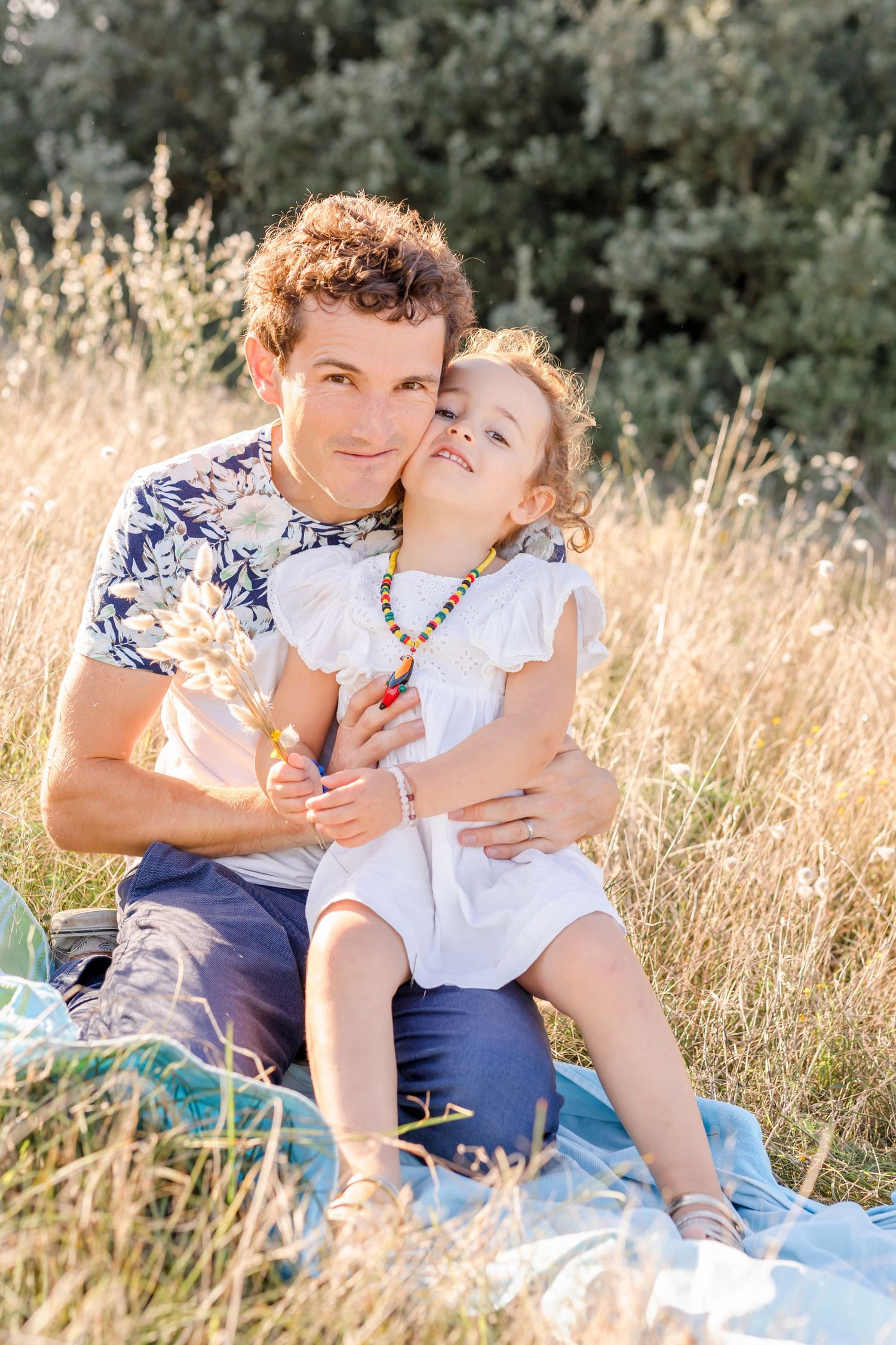 Parent and child sharing tender moment while sitting in sunny meadow.