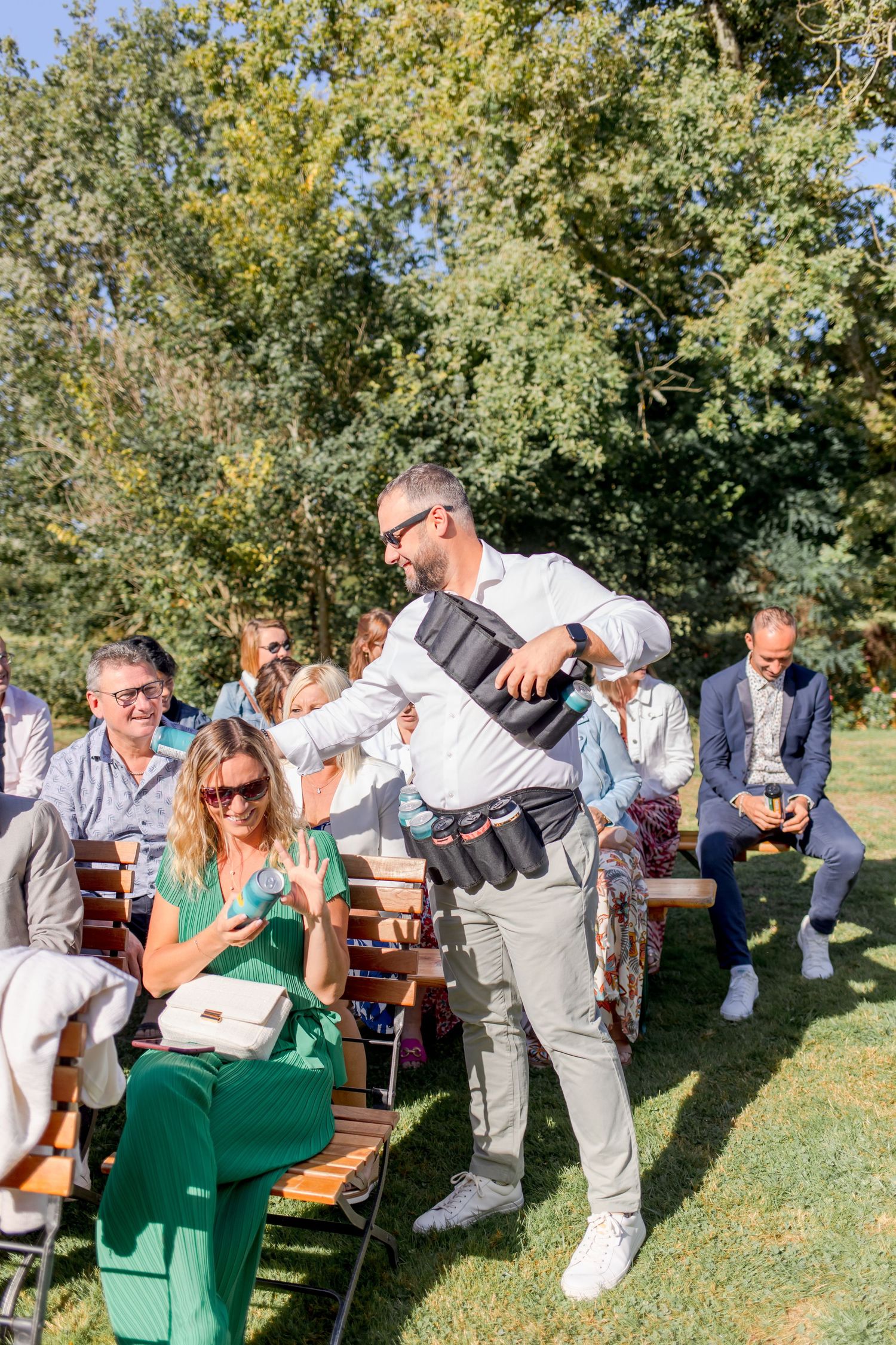 Wedding guests seated on wooden benches during an outdoor celebration.