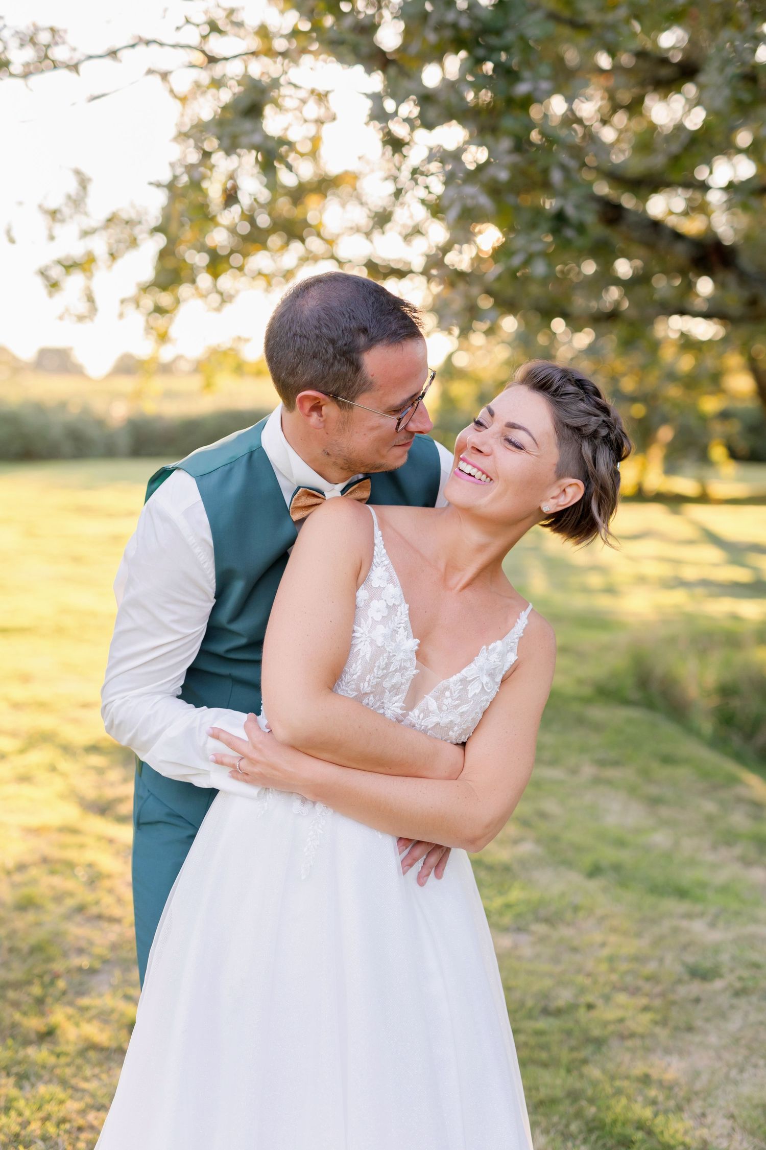 Joyful wedding couple laughing together in late afternoon sunlight.