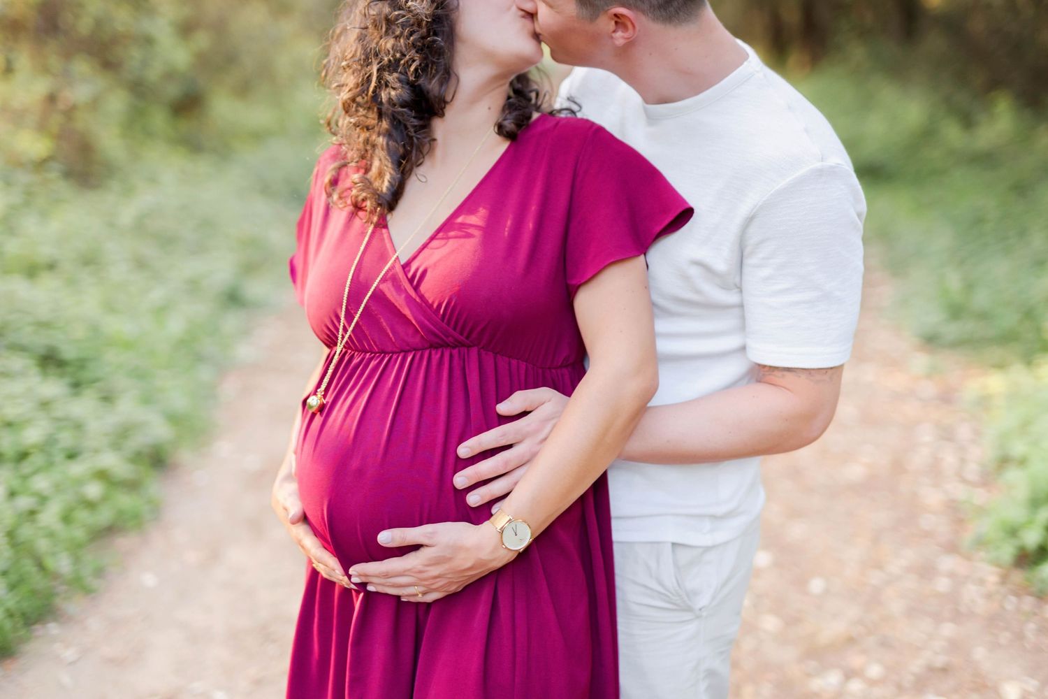 Intimate maternity portraits showing tender moments between a couple on a wooded pathway.