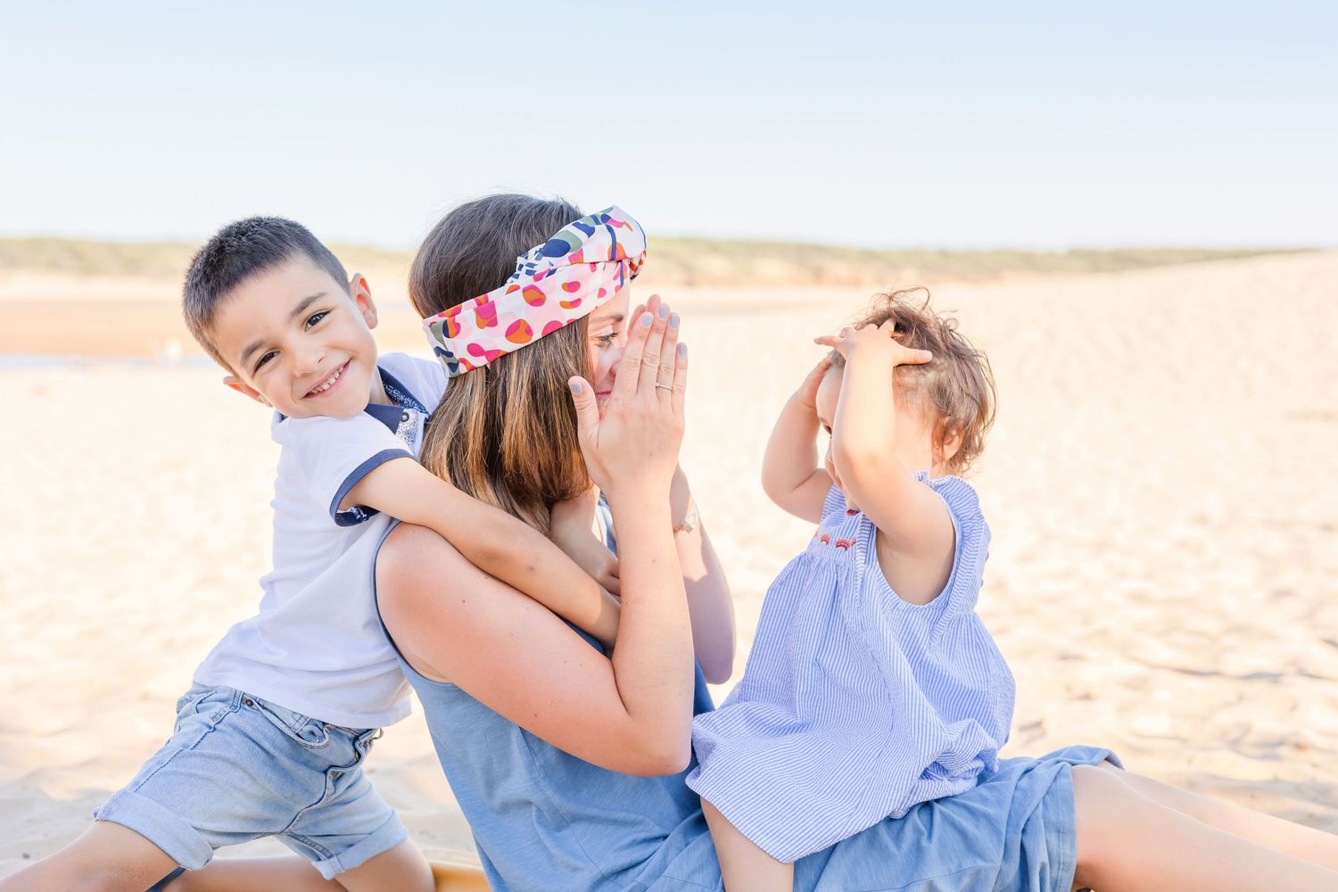 Family enjoying a playful moment together on a sandy beach during golden hour.