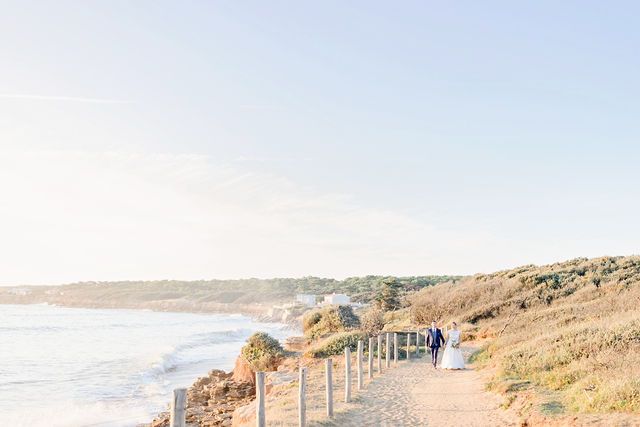 Coastal path with wooden railings along ocean cliffs in soft pastel lighting.