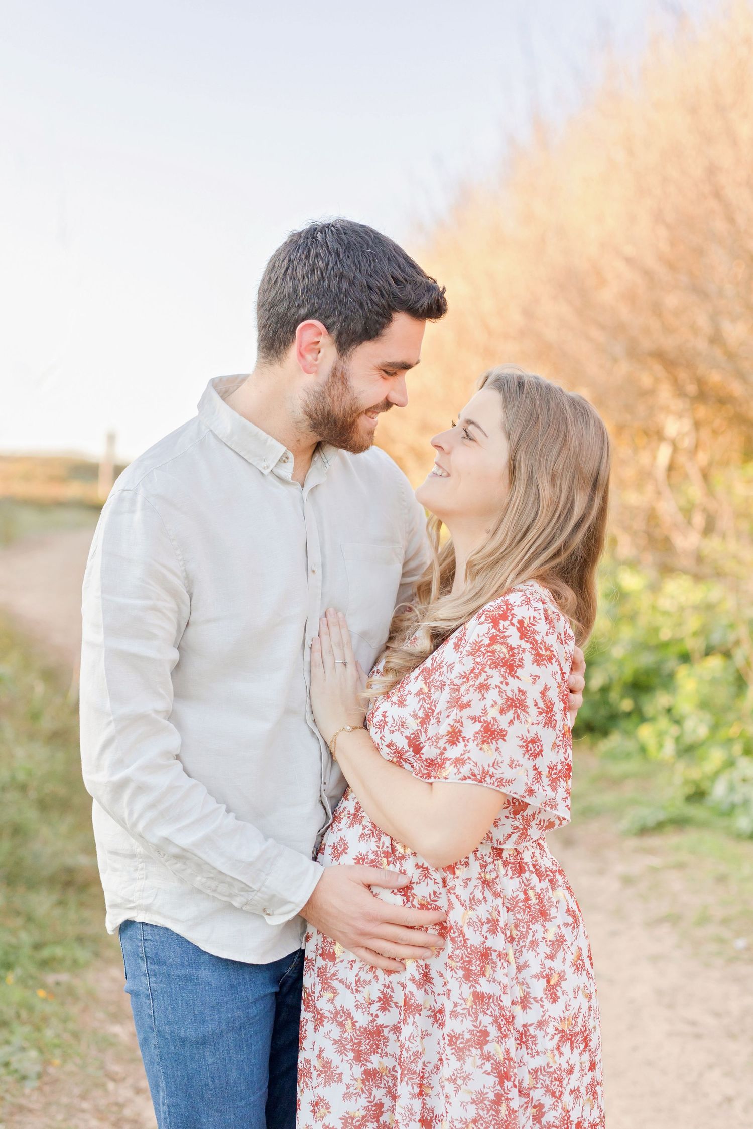 A romantic outdoor photoshoot during golden hour with autumn foliage in the background.