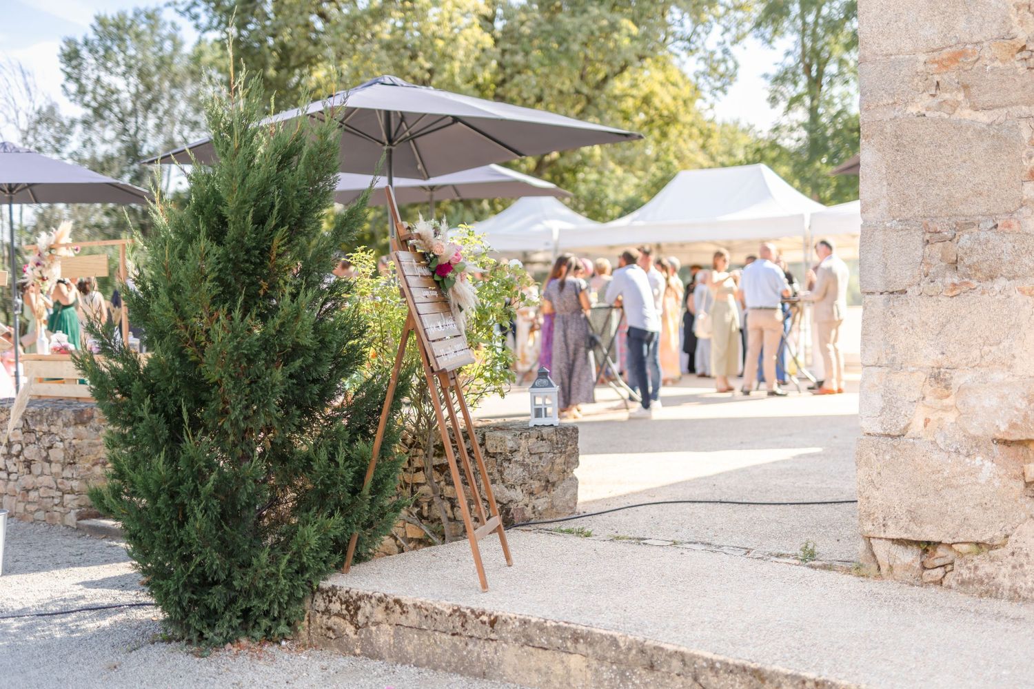 Outdoor wedding venue with stone walls, umbrellas, and evergreen landscaping.