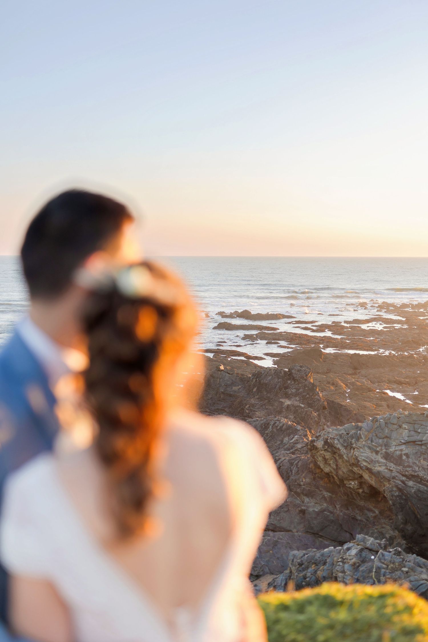 Romantic coastal landscape with couple in soft focus during sunset.