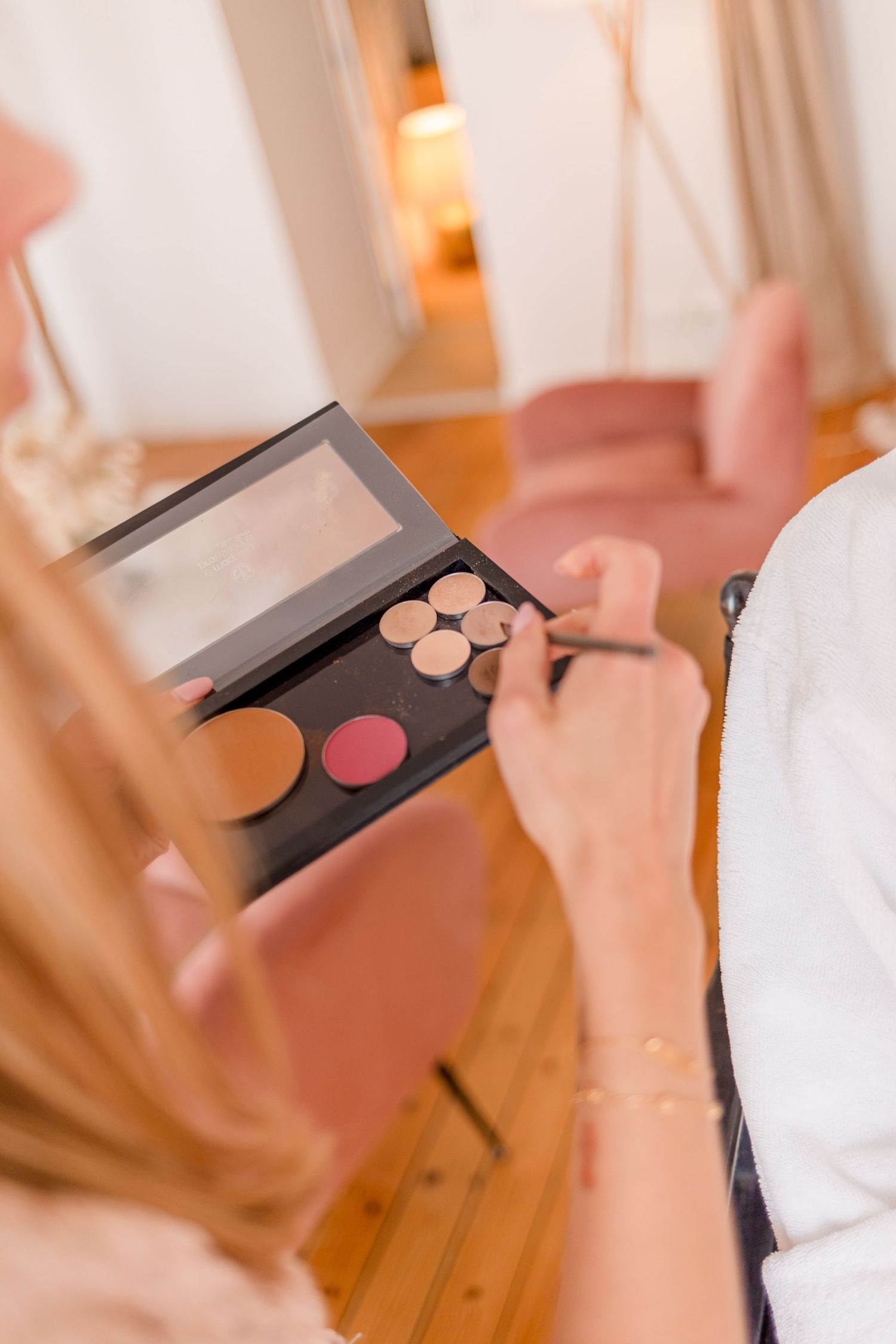 Close-up of hands selecting colors from a professional makeup palette.