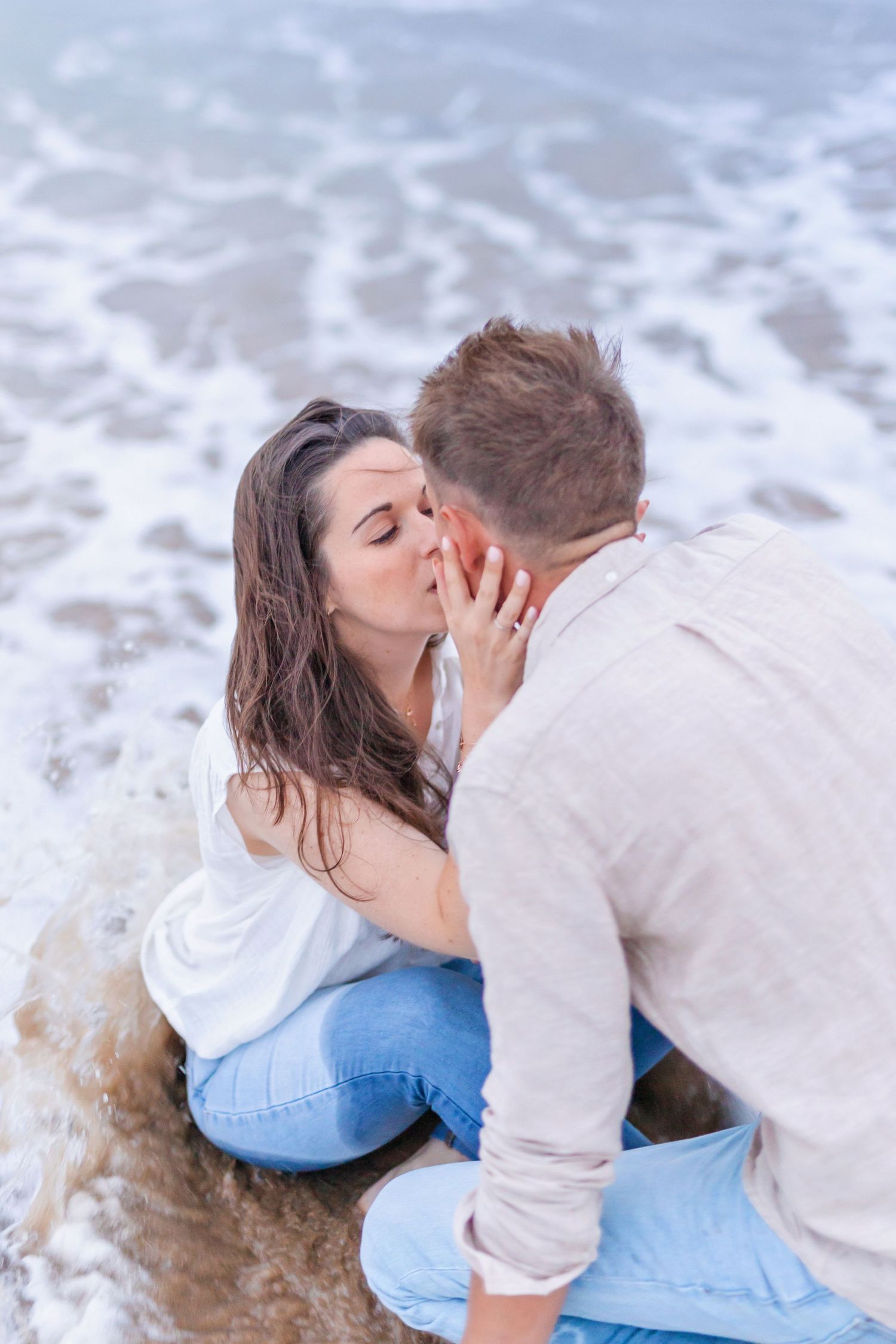 An intimate scene between two people sitting by the ocean waves.