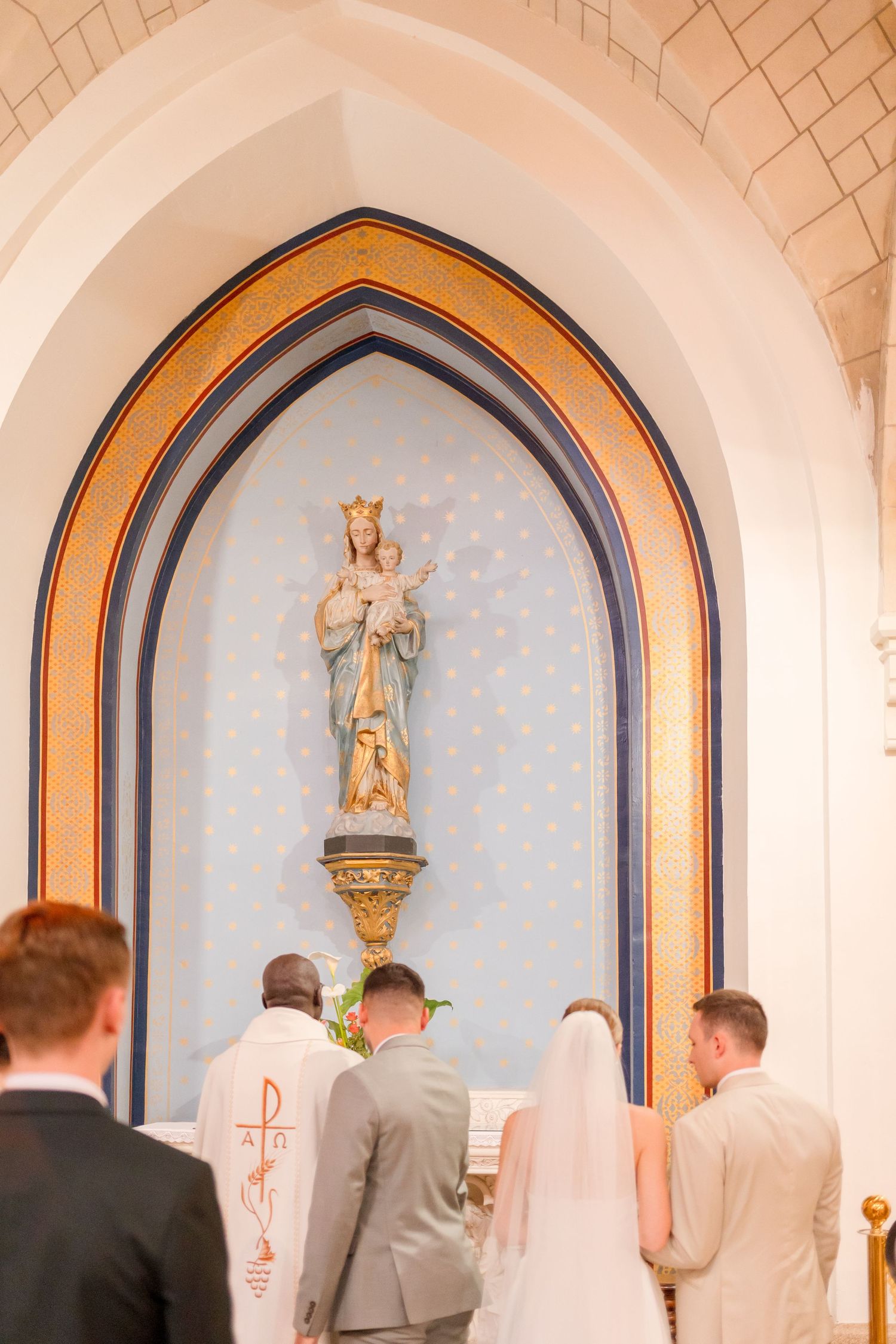 Religious statue in ornate church alcove during wedding ceremony.