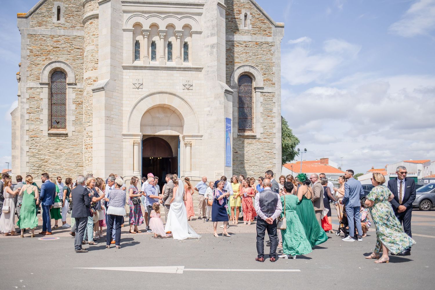Wide shot of wedding guests gathered outside historic stone church.