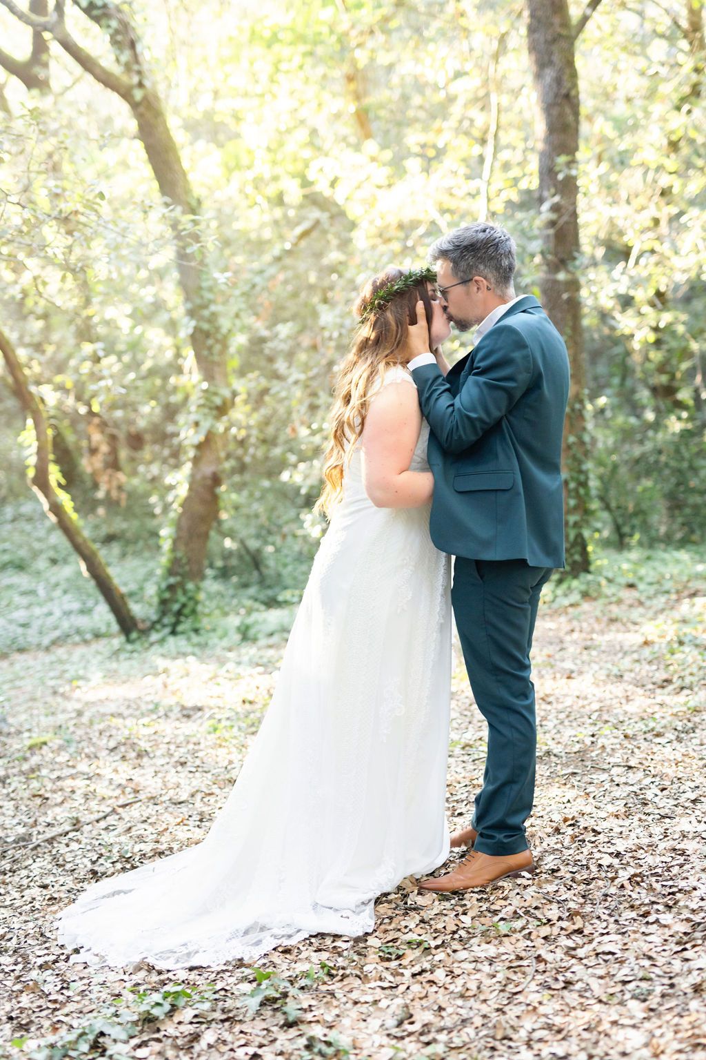 Tender wedding moment captured in golden forest light with couple in embrace.