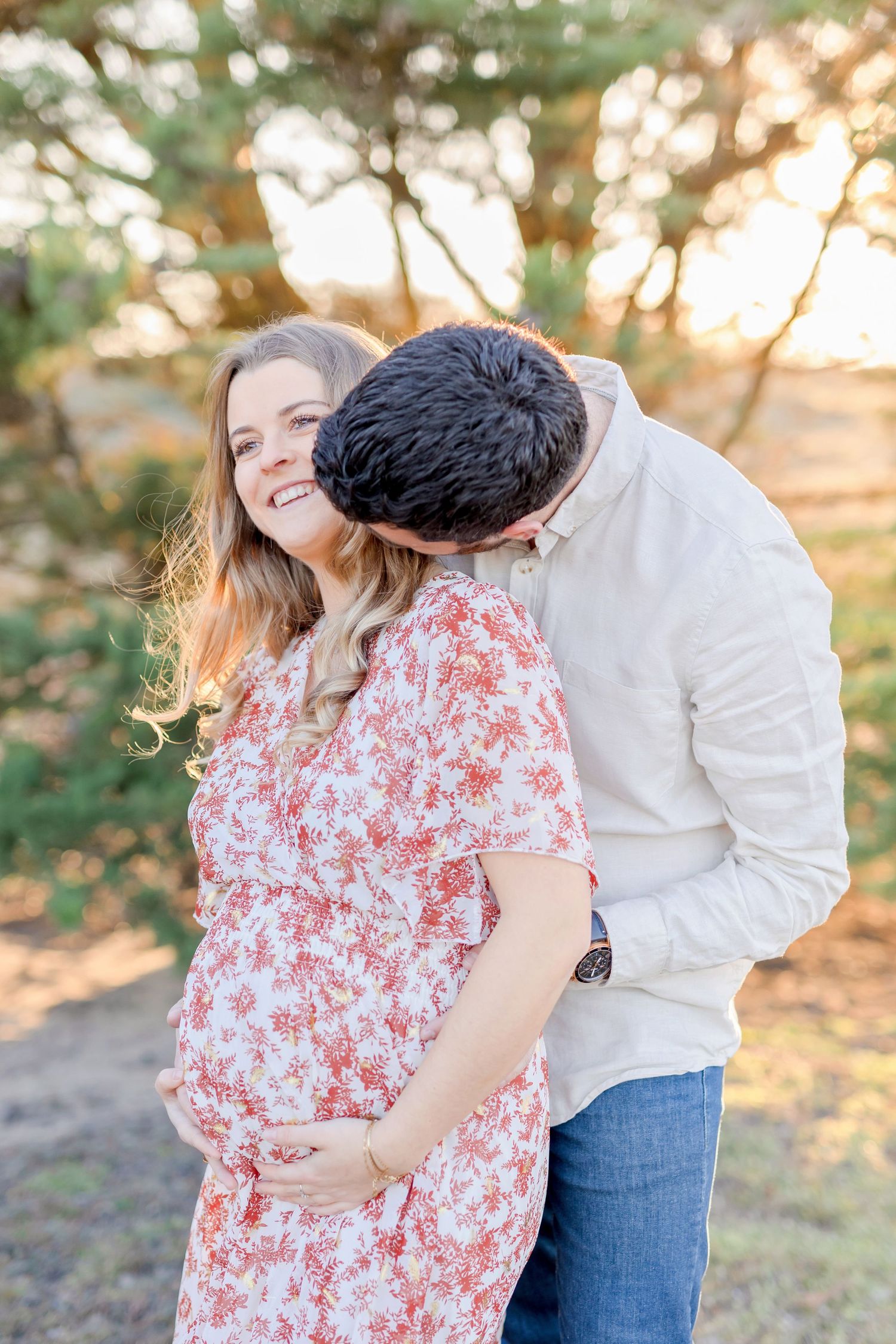 Intimate maternity photo of couple laughing together in natural setting.