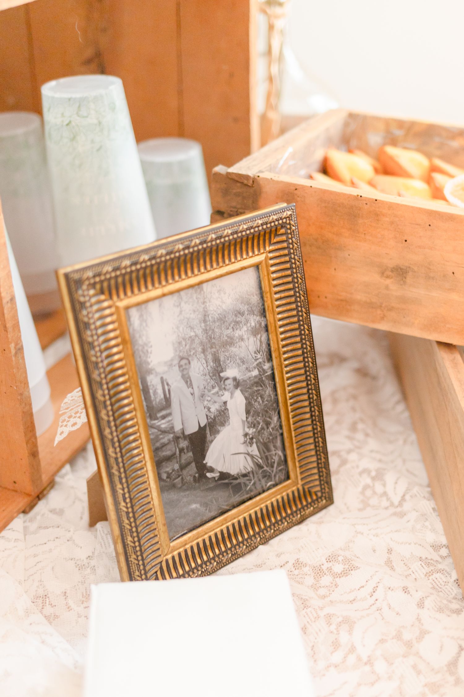 Antique gold-framed photograph on display with rustic wooden crates and white containers.