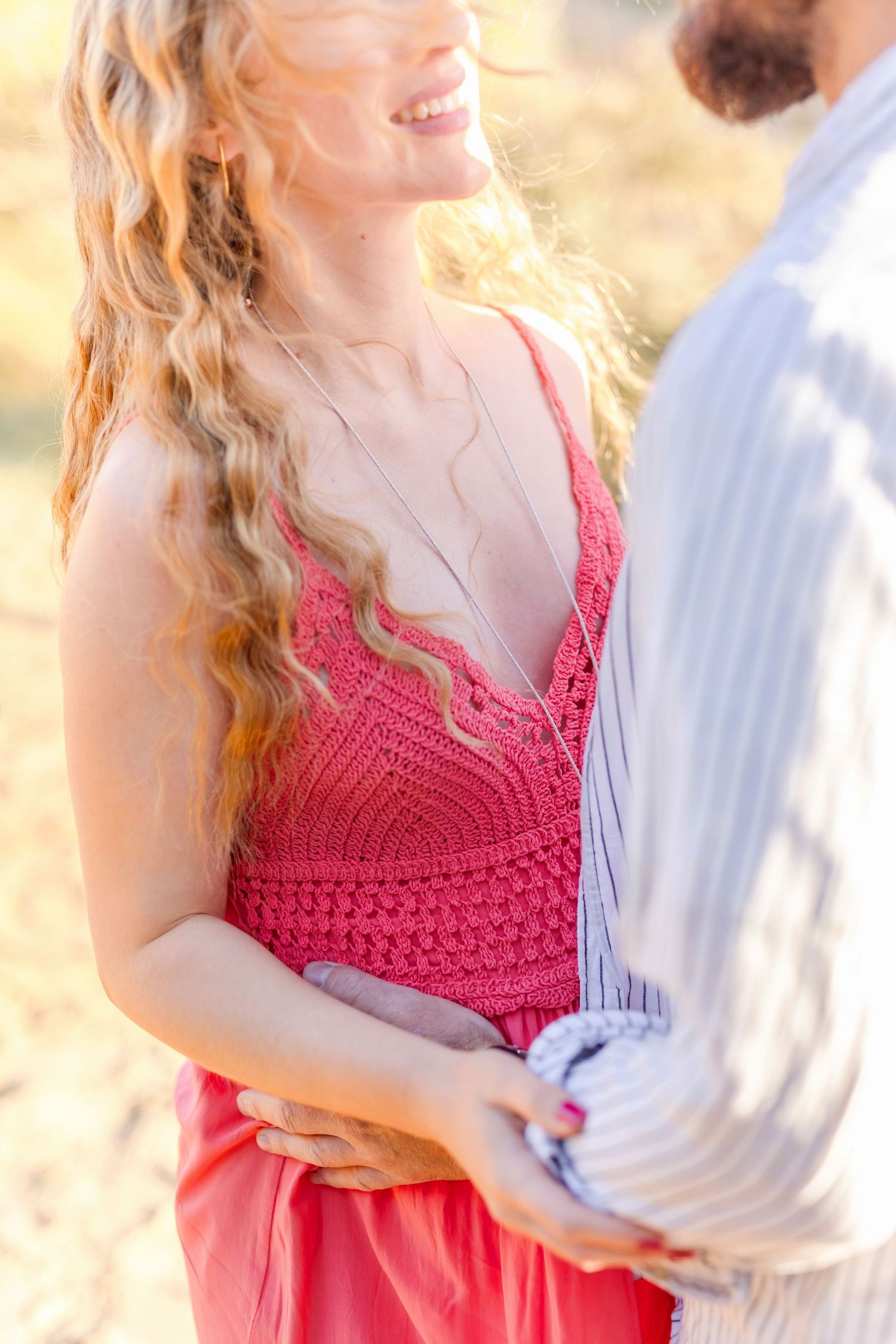 Close-up detail of coral crochet dress during romantic outdoor photoshoot.