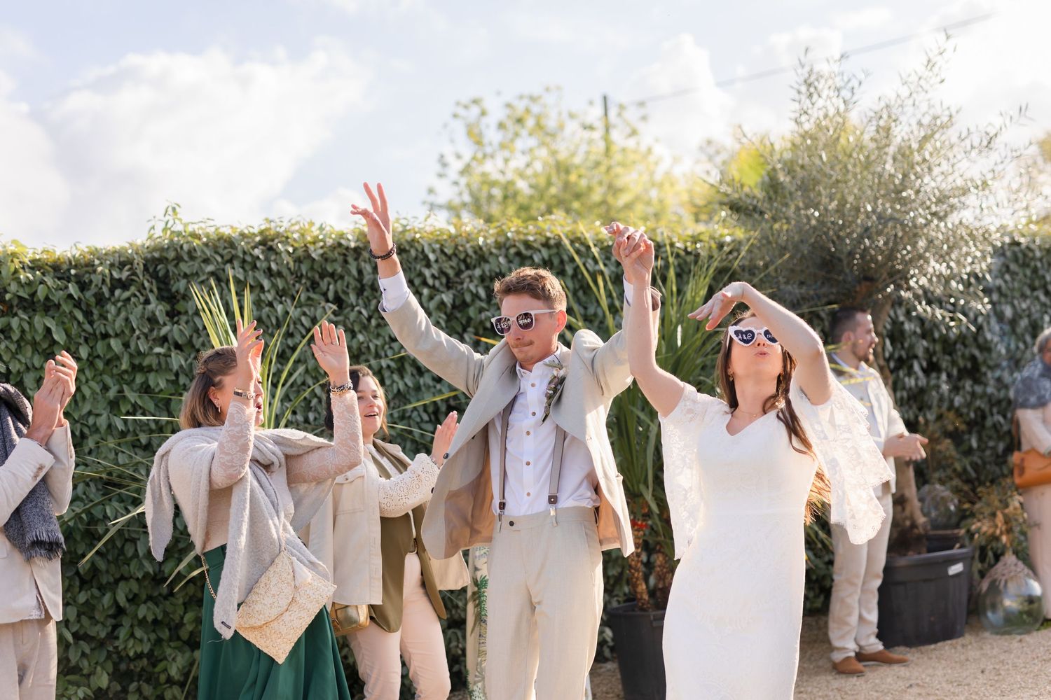 Celebratory moment at an outdoor wedding with guests raising hands in joy.