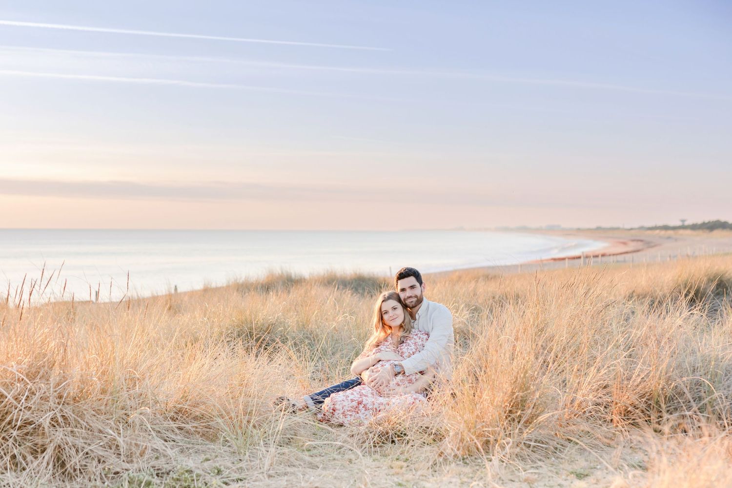 Couple sharing intimate moment on coastal hillside during sunset.