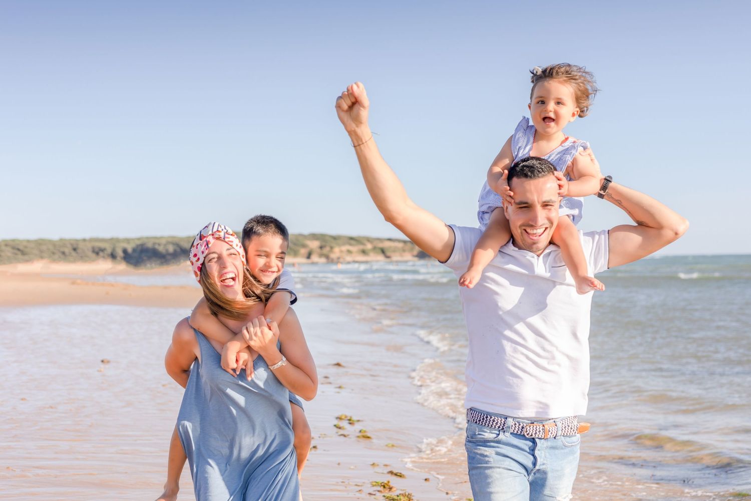 Playful moments on a beach with people enjoying piggyback rides against a scenic coastal backdrop.