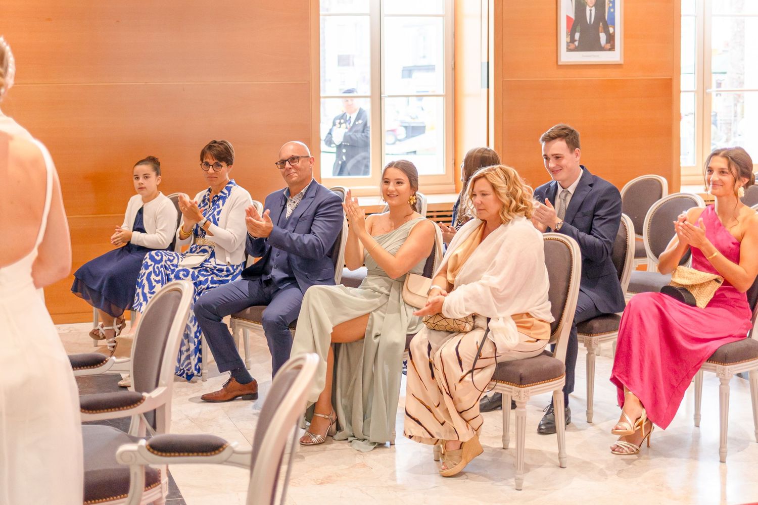 Wedding guests seated in chairs watching the ceremony in an orange-tinted room.