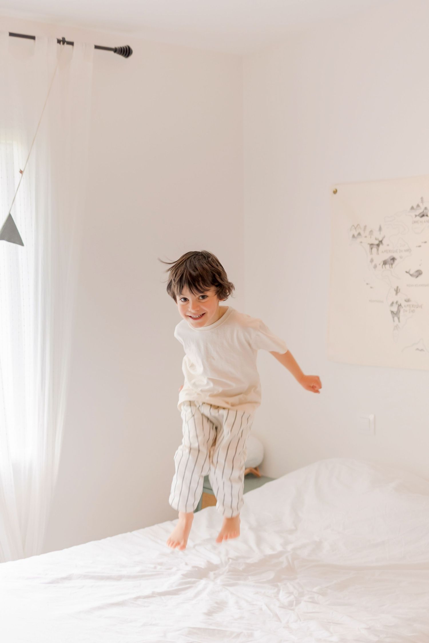 A playful sequence of jumping and bouncing on a white bed in a bright minimalist room.