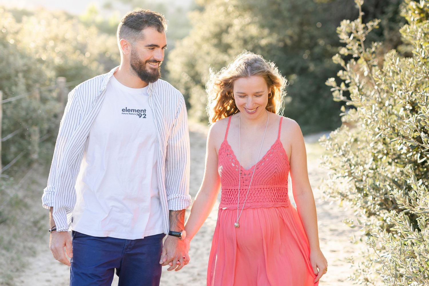 A romantic couple walking together on a sunlit nature path.