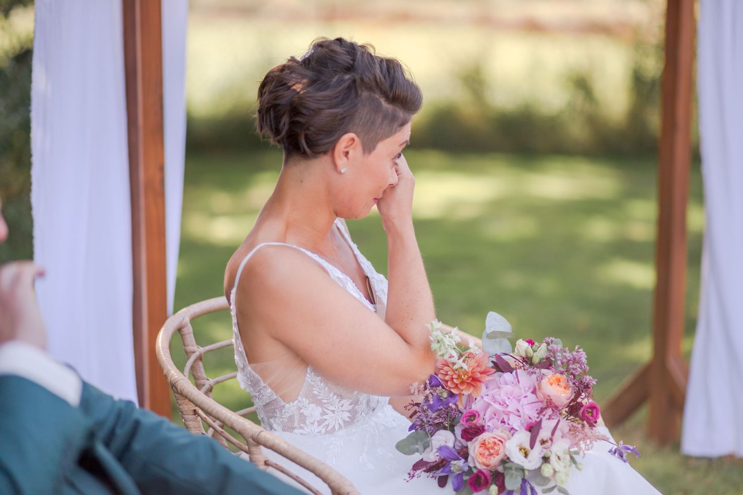 Emotional moment captured during outdoor wedding ceremony with floral bouquet.