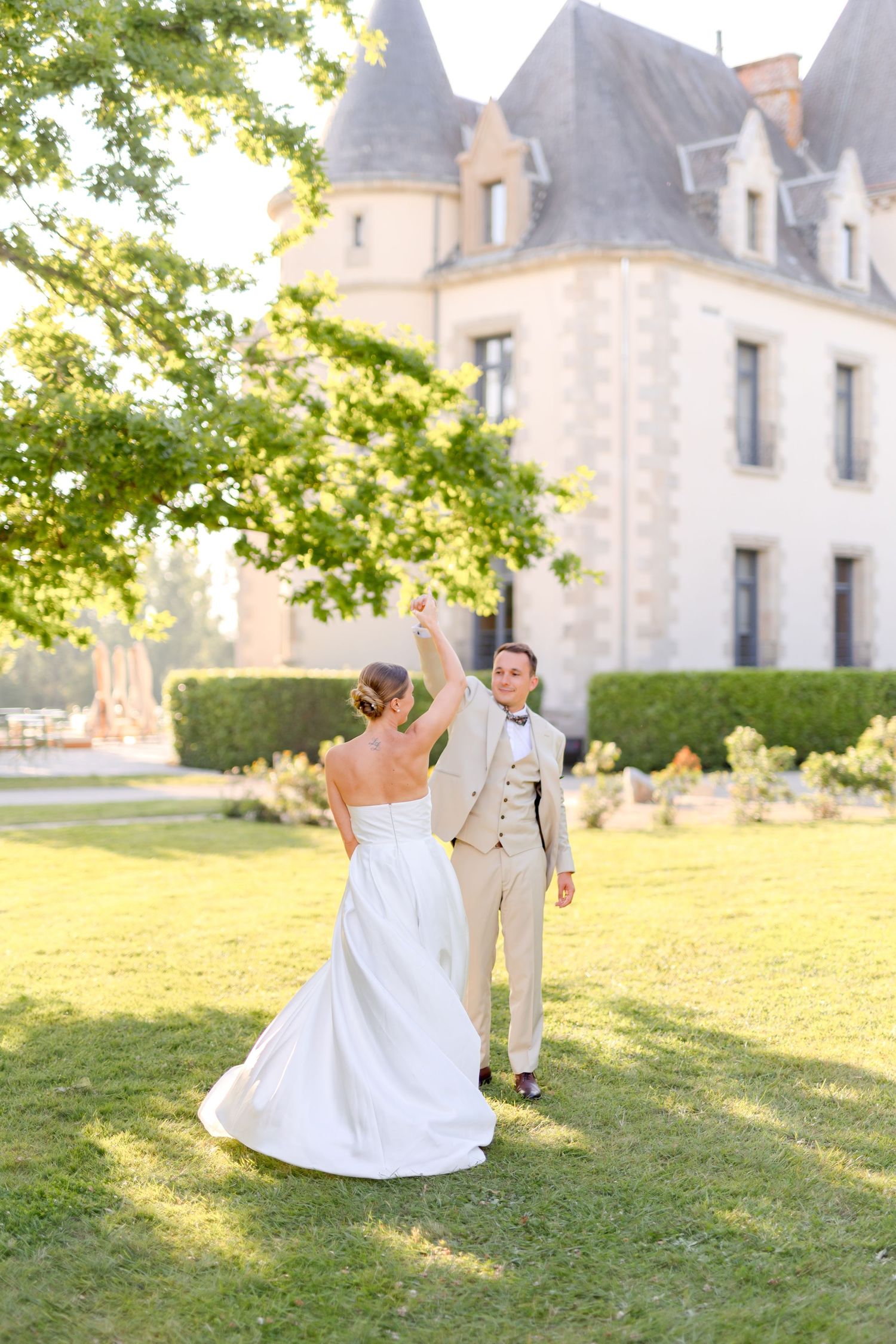 A couple shares a romantic moment on the grounds of a French chateau during their wedding.