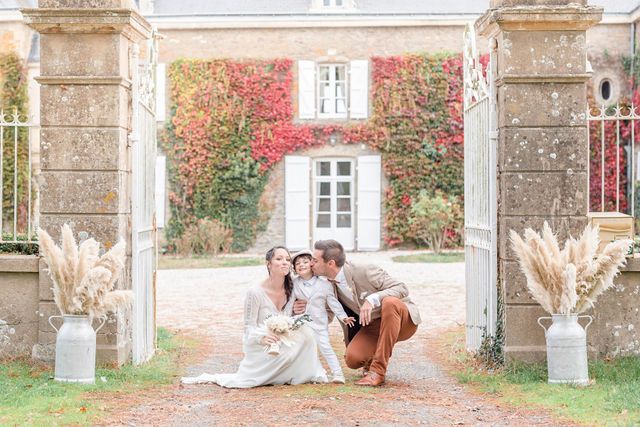Dreamy family moment captured between decorated stone pillars at French estate.