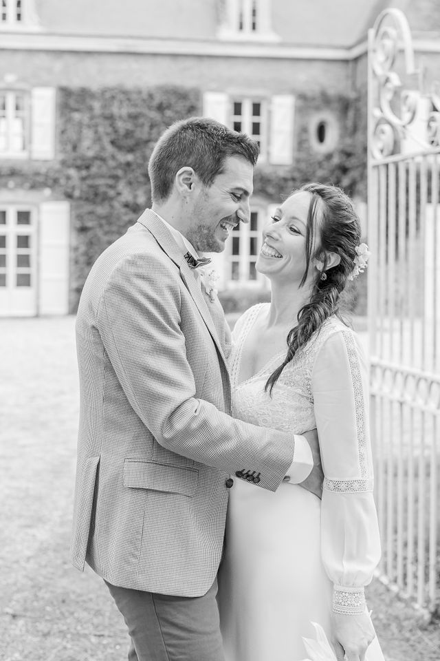 Black and white wedding portrait series against stone pillars and iron gates.