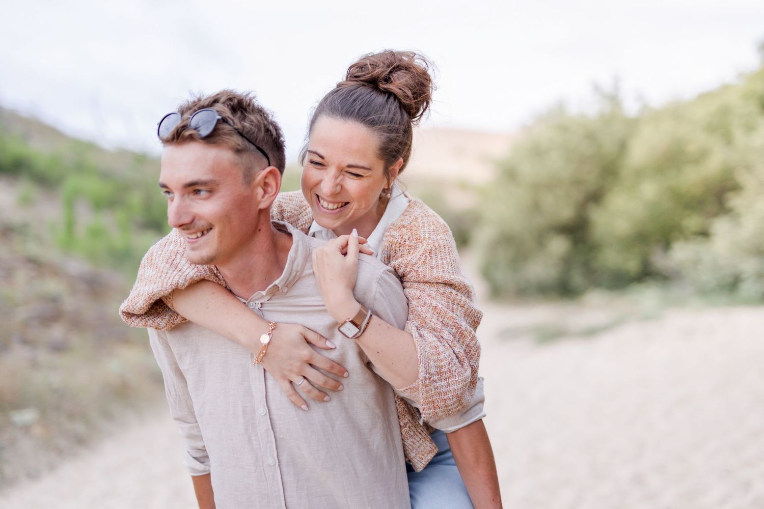 Happy couple enjoying piggyback ride on sunny nature path.