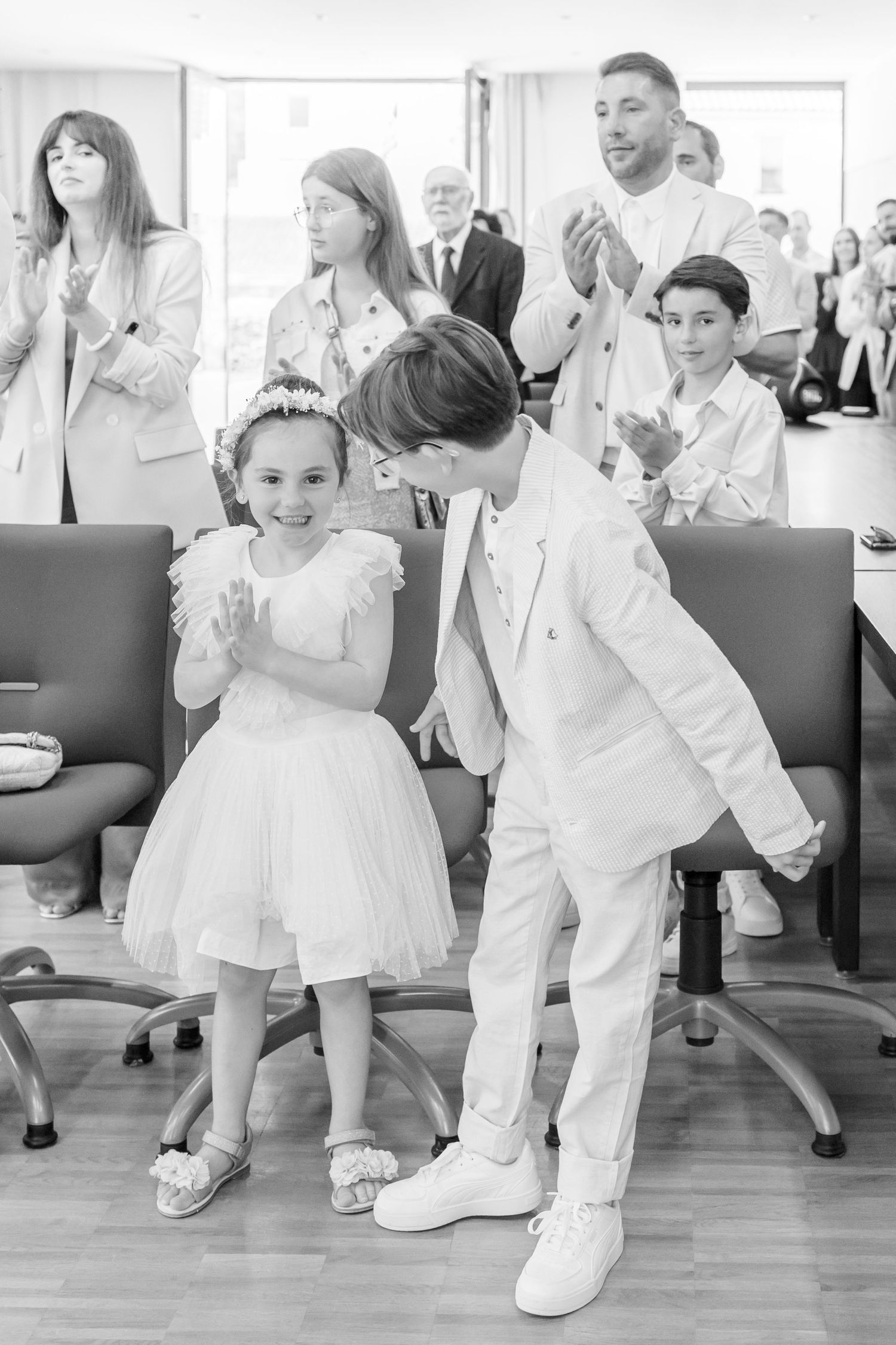 Children dancing in formal white outfits at a wedding celebration.