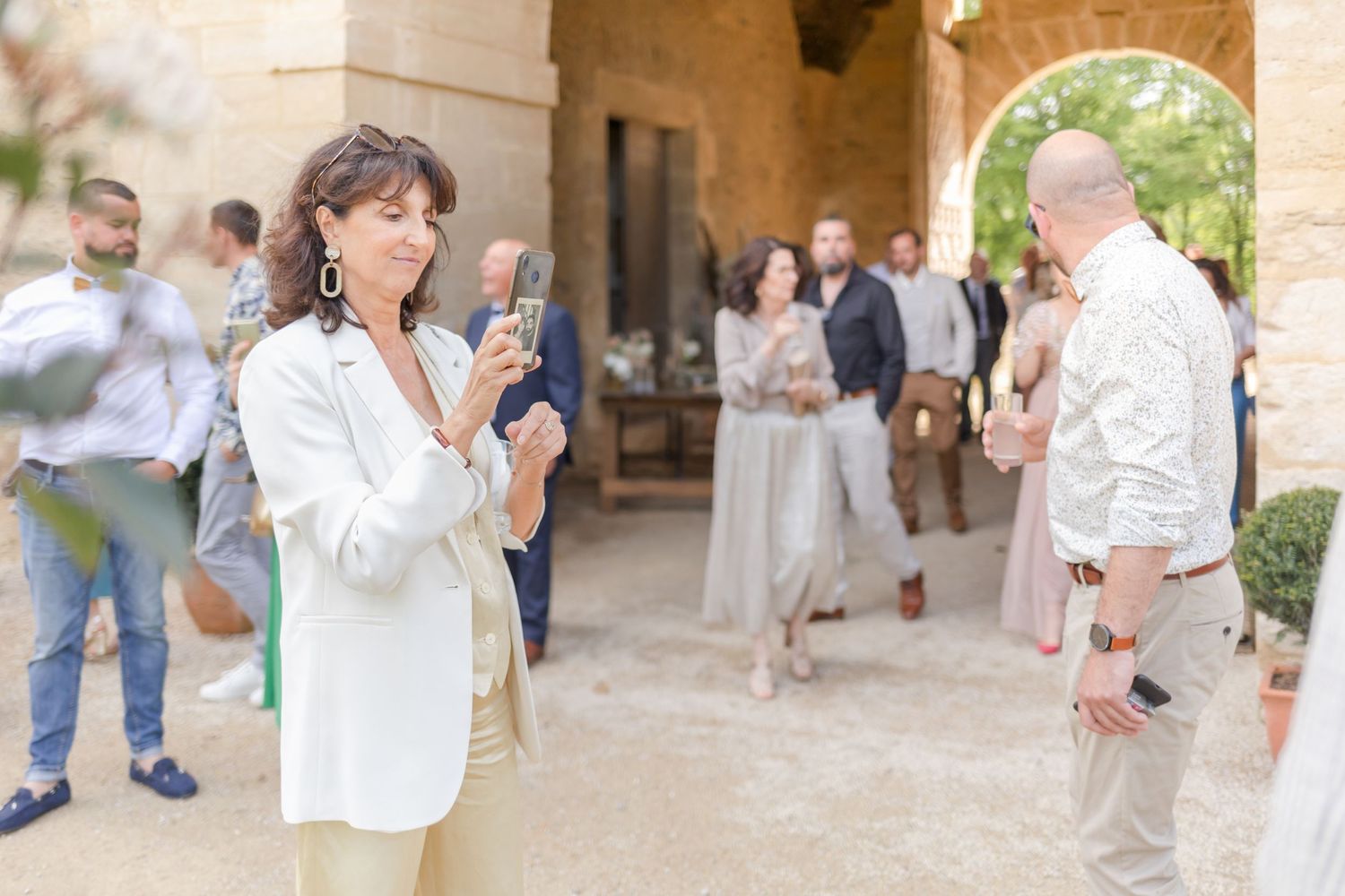 Outdoor event with guests mingling in an elegant stone archway setting.