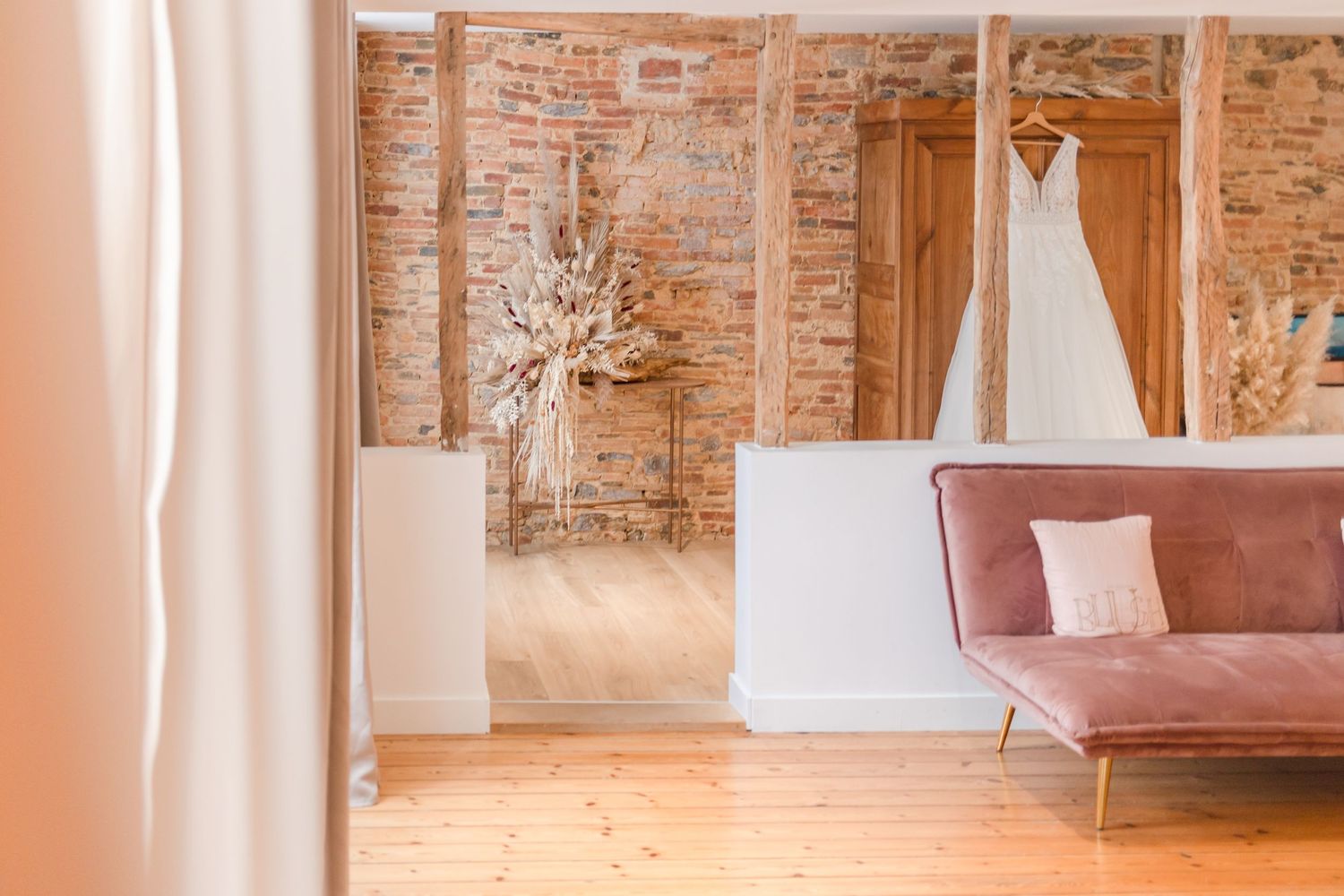 Wedding dress display room with exposed brick walls and pink velvet couch.