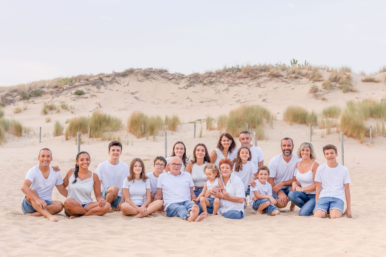 Large family group poses together on desert sand dunes wearing matching blue and white clothing.