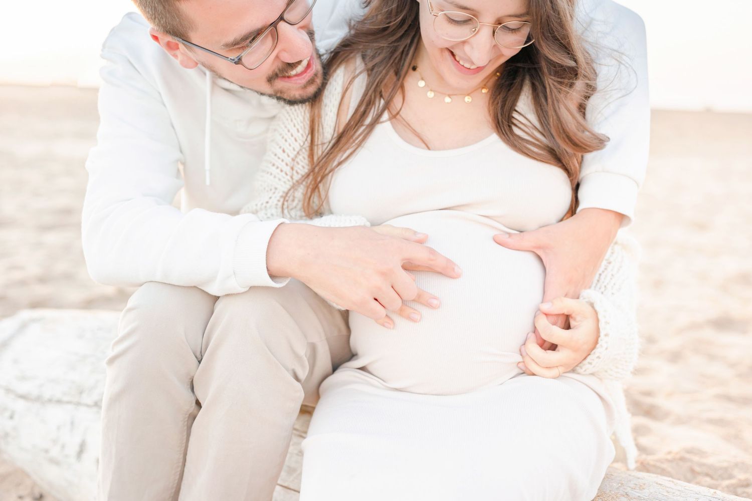 Couple sharing an intimate moment on the beach during a maternity photoshoot.