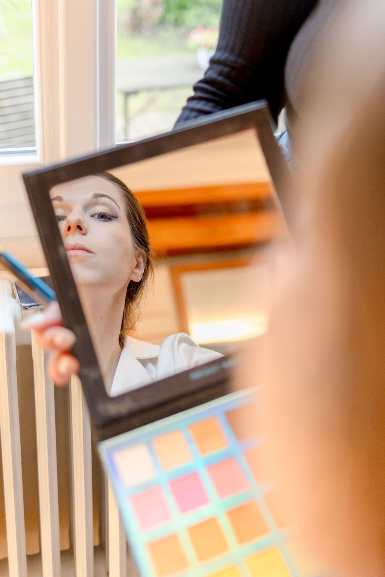 A makeup artist uses a cosmetic palette to apply eye shadow from multiple angles.